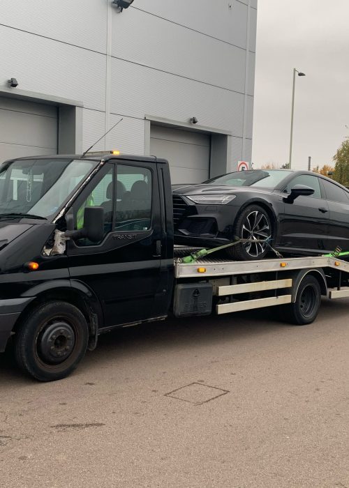 Vehicle recovery specialist helping a car stuck in a parking area.